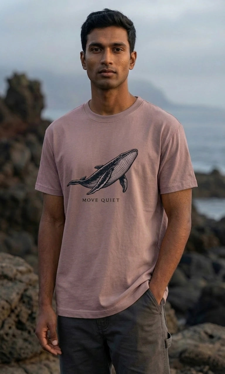 Man wearing a pink t-shirt with a whale graphic and text, standing outdoors.